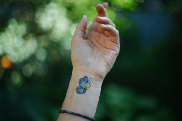 A butterfly tattoo adorns a wrist.